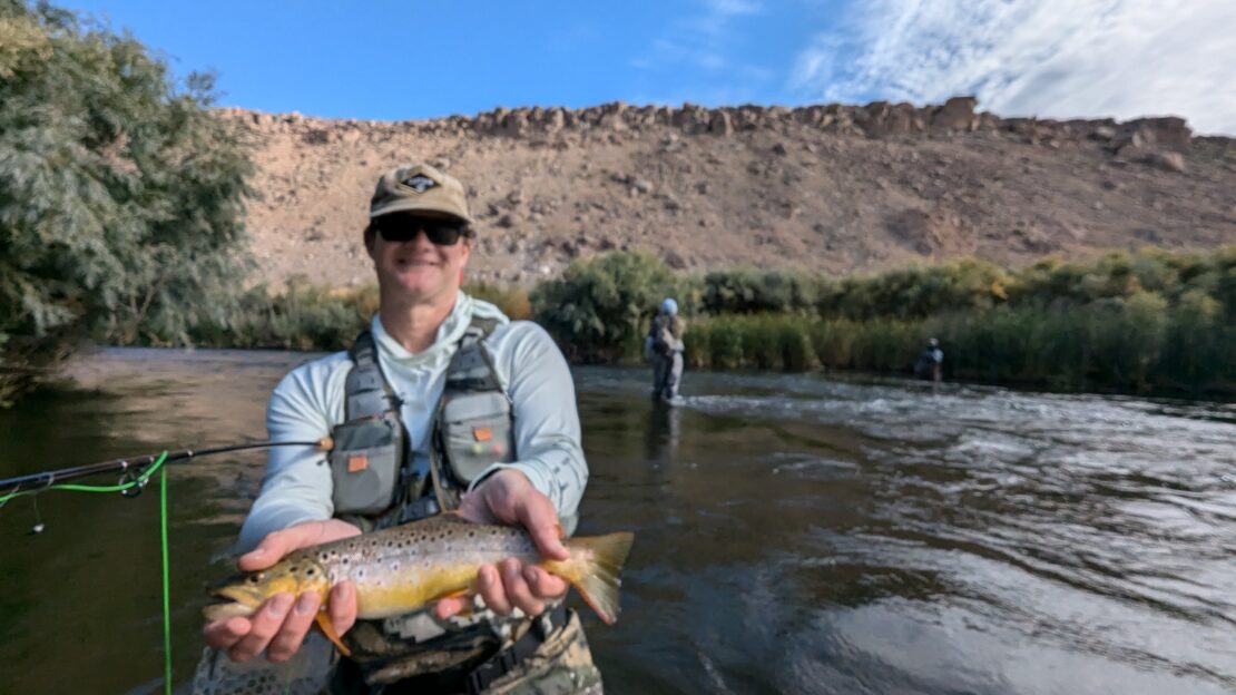 Lower Owens in the Fall near bishop california. Man in water holds up brown trout